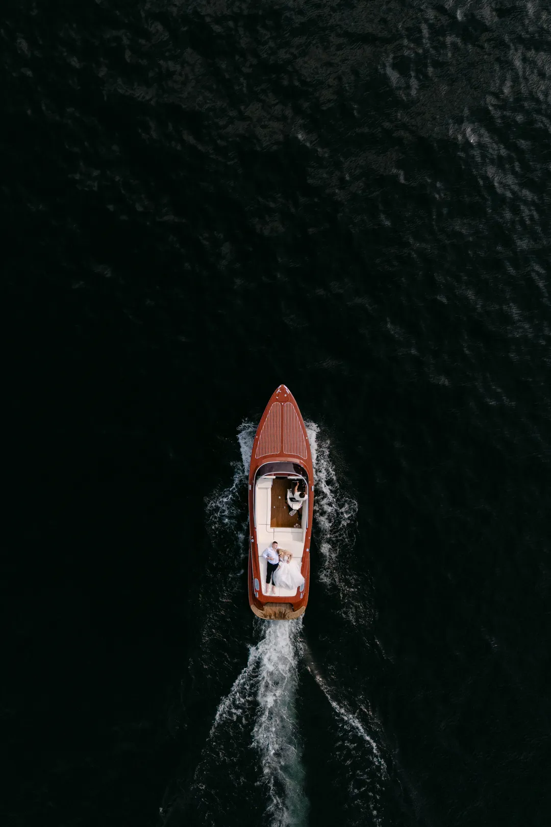 Para młoda w drewnianej motorówce na jeziorze Como — ujęcie z drona