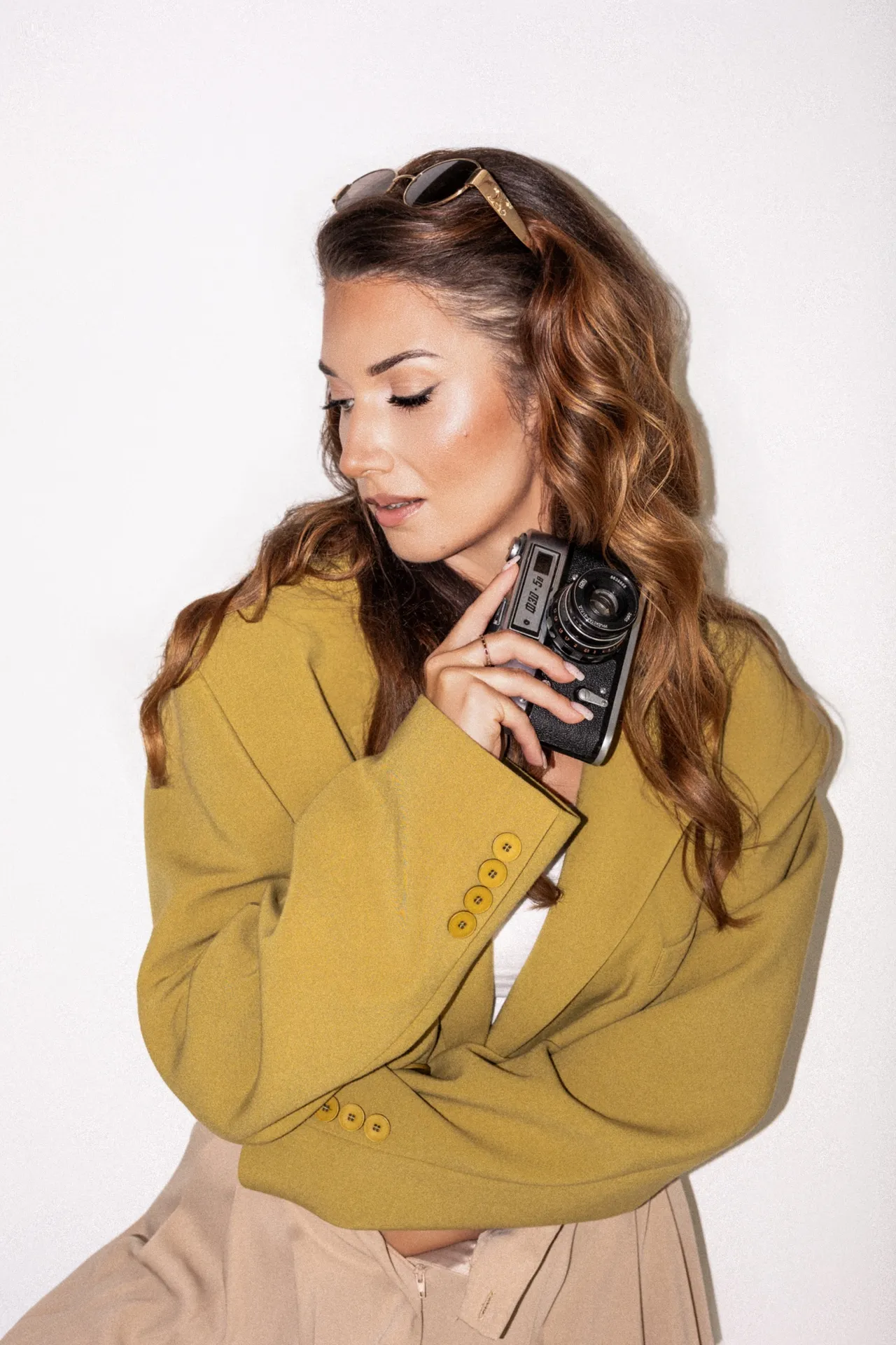 Adrianna Czesny, fotografka, w musztardowej marynarce, z aparatem w dłoni